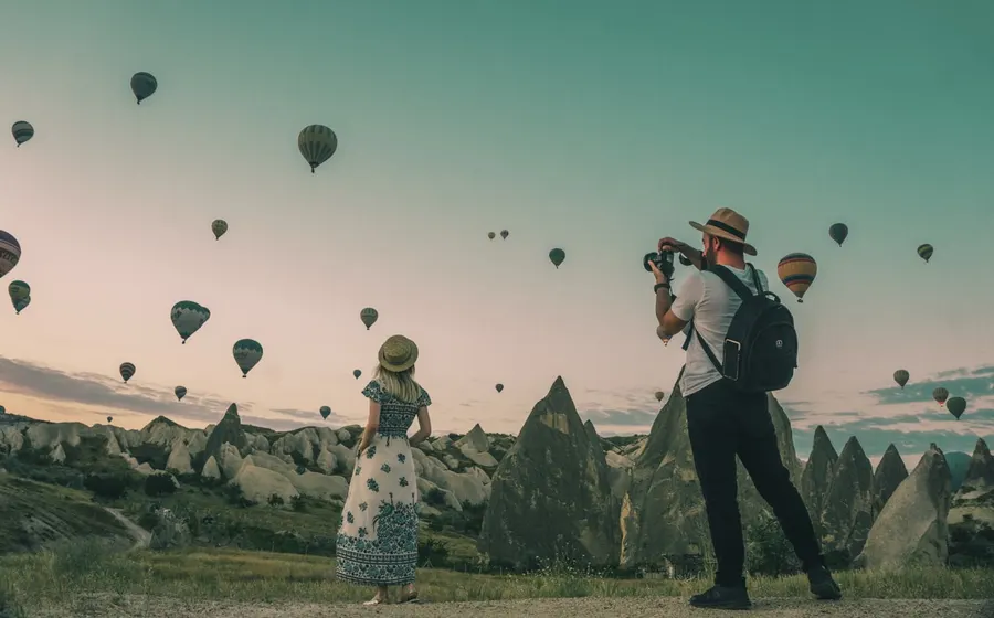 Travellers discovering a scenic destination filled with hot-air balloons