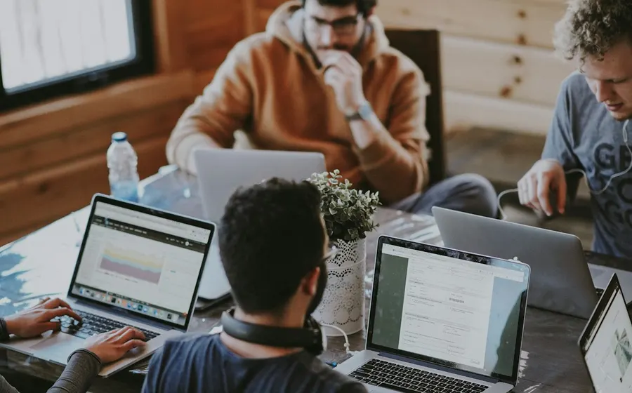 Friends working together around a table with laptops